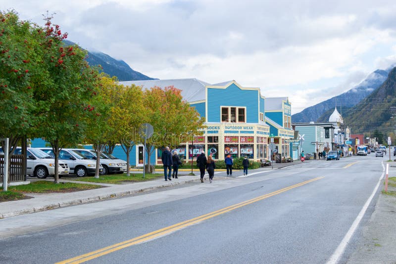 Mensen en auto's het drijven die door de winkels op Main Street in Skagway Alaska lopen royalty-vrije stock afbeeldingen Mensen en auto's het drijven die door de winkels op Main Street in Skagway Alaska lopen royalty-vrije stock afbeeldingen