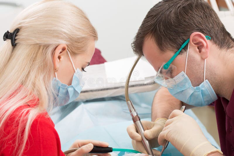 Mensen, geneeskunde, de stomatologie en gezondheidszorgconcept - mannelijke tandarts en medewerker die met speekseluitwerper wijf stock foto Mensen, geneeskunde, de stomatologie en gezondheidszorgconcept - mannelijke tandarts en medewerker die met speekseluitwerper wijf stock foto