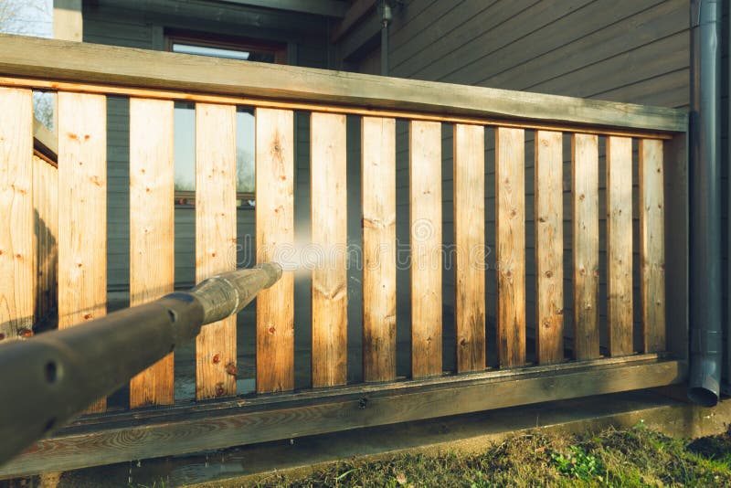 Mensen schoonmakend terras met een machtswasmachine - de reinigingsmachine van de hoogwaterdruk op houten terrastraliewerk stock afbeeldingen Mensen schoonmakend terras met een machtswasmachine - de reinigingsmachine van de hoogwaterdruk op houten terrastraliewerk stock afbeeldingen