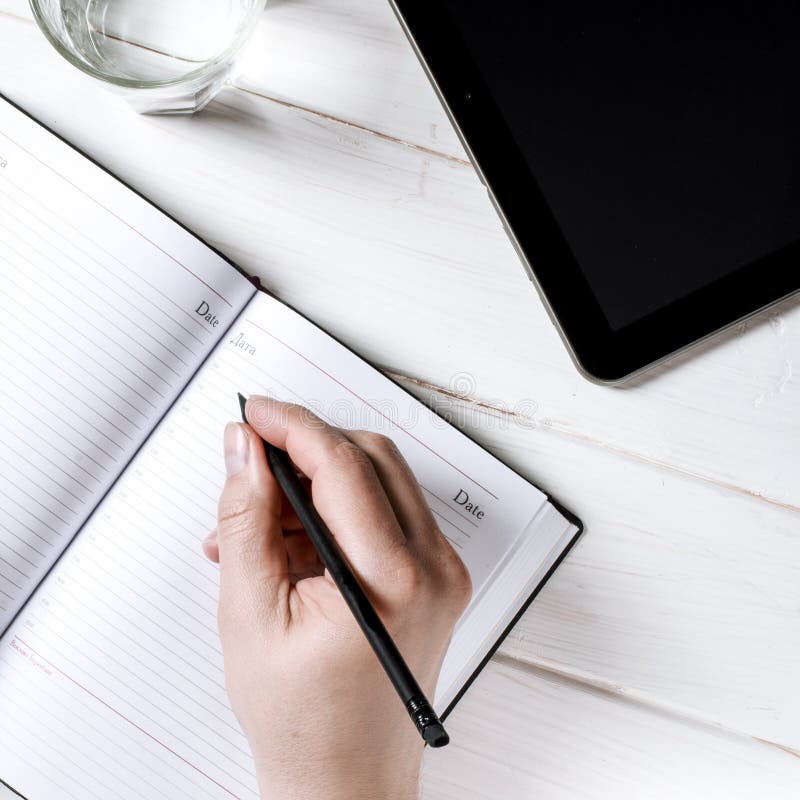 Mensenhanden die nota's schrijven aan het notitieboekje op houten lijst in huisbureau stock afbeeldingen Mensenhanden die nota's schrijven aan het notitieboekje op houten lijst in huisbureau stock afbeeldingen