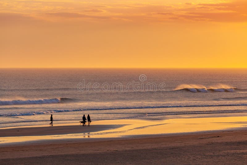 Mensensilhouetten en brekende oceaangolven op het strand bij zonsondergang royalty-vrije stock fotografie Mensensilhouetten en brekende oceaangolven op het strand bij zonsondergang royalty-vrije stock fotografie