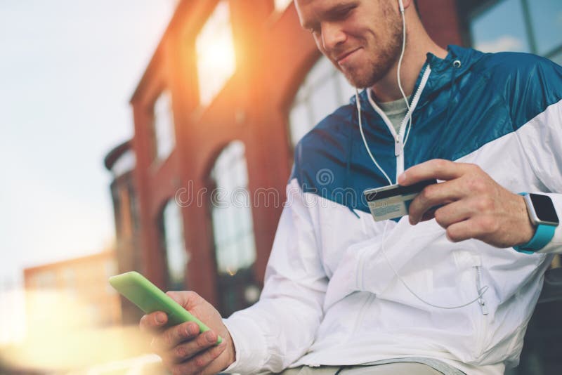 Mensenzitting in openlucht met creditcard en mobiele telefoon, Internet-bankwezen en online het winkelen royalty-vrije stock foto's Mensenzitting in openlucht met creditcard en mobiele telefoon, Internet-bankwezen en online het winkelen royalty-vrije stock foto's
