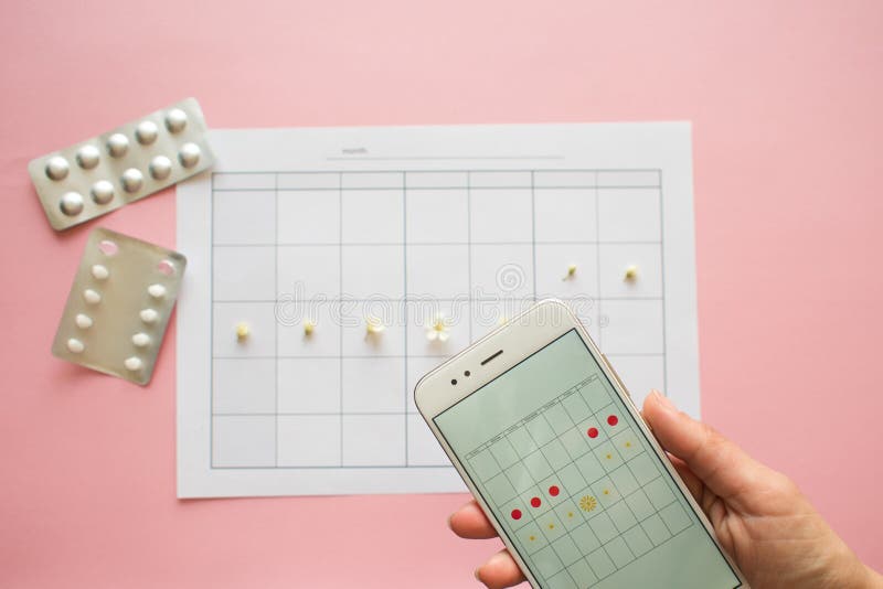 Menstrual cycle. Calendar for the month with marks and a mobile application on the smartphone screen. stock photos