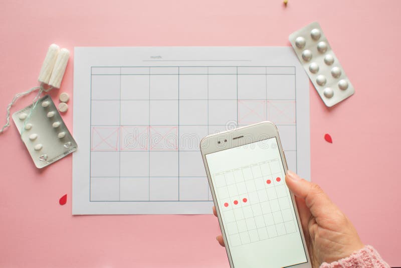 Menstrual cycle. Calendar for the month with marks and a mobile application on the smartphone screen. stock photos