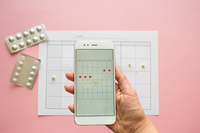 Menstrual cycle. Calendar for the month with marks and a mobile application on the smartphone screen. stock photo