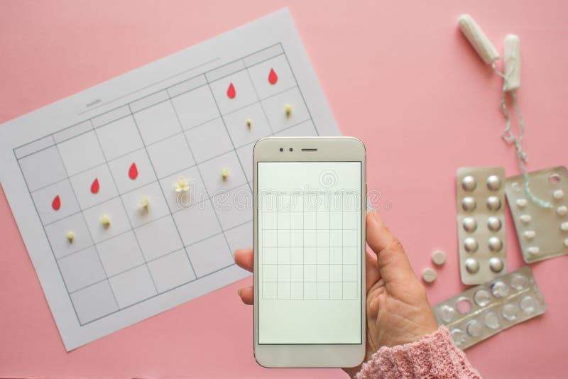 Menstrual cycle. Calendar for the month with marks and a mobile application on the smartphone screen. royalty free stock image