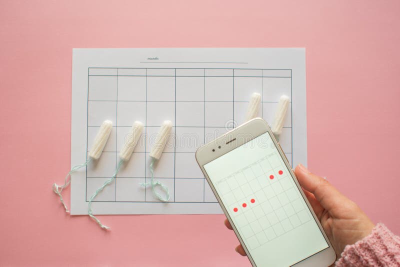 Menstrual cycle. Calendar for the month with marks and a mobile application on the smartphone screen. royalty free stock image