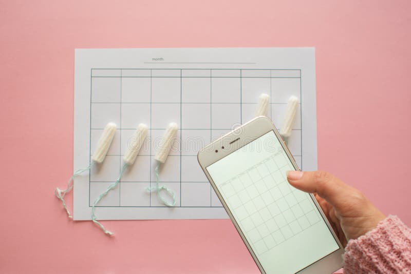 Menstrual cycle. Calendar for the month with marks and a mobile application on the smartphone screen. royalty free stock images