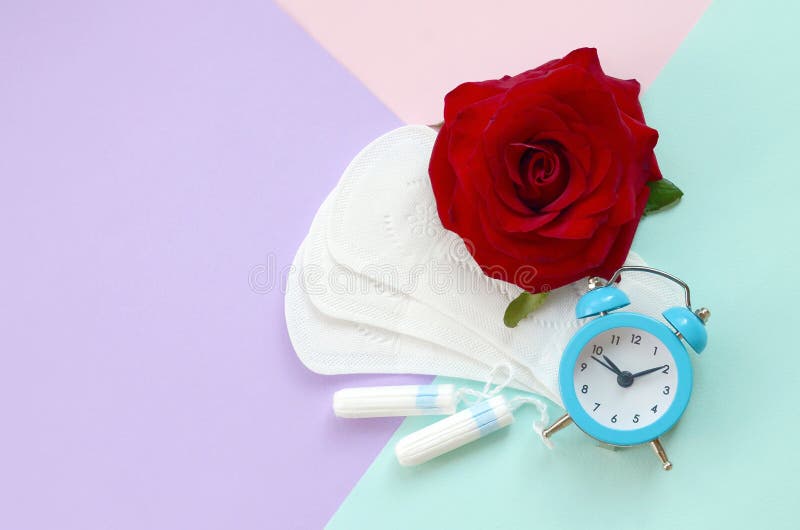 Menstrual pads and tampons with blue alarm clock and red rose flower on multicolored background