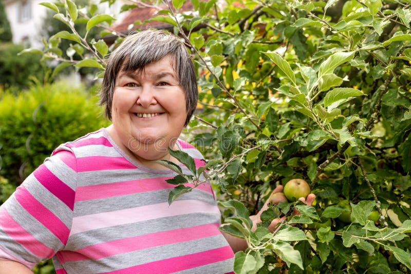 Mental disabled woman is showing a apple on a apple tree