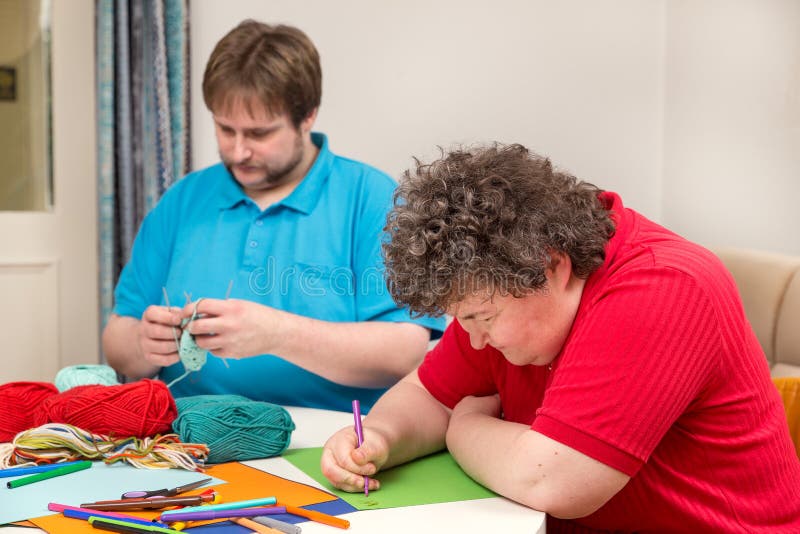 A mentally disabled women and young men doing arts and crafts