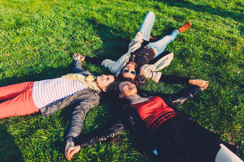 Mentira feliz de los adolescentes comparativa en sus partes posteriores en la hierba verde fotografía de archivo Mentira feliz de los adolescentes comparativa en sus partes posteriores en la hierba verde fotografía de archivo