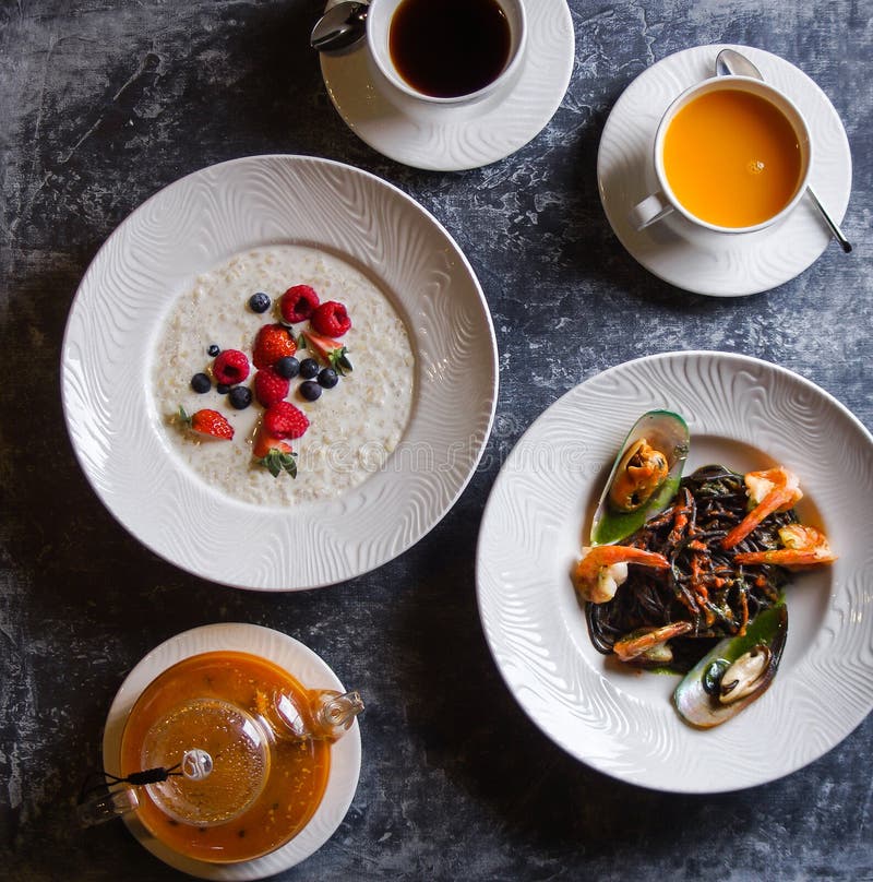 Menu at the cafe, Breakfast and lunch, Porridge with berries and pasta with seafood, Bulgur and black spaghetti with shrimps. Flatlay, Top view, Moody on royalty free stock image Menu at the cafe, Breakfast and lunch, Porridge with berries and pasta with seafood, Bulgur and black spaghetti with shrimps. Flatlay, Top view, Moody on royalty free stock image