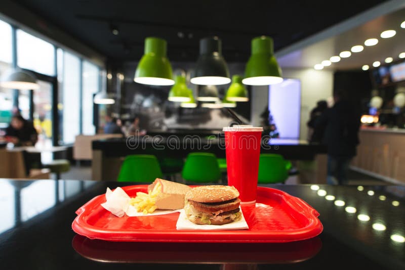 Fast food menu on the table tray at the fast food restaurant. Burger, French fries and a glass cola in the fast food restaurant.Fast Food Concept.Tray junk food restaurant in background. Fast food menu on the table tray at the fast food restaurant. Burger, French fries and a glass cola in the fast food restaurant.Fast Food Concept.Tray junk food restaurant in background