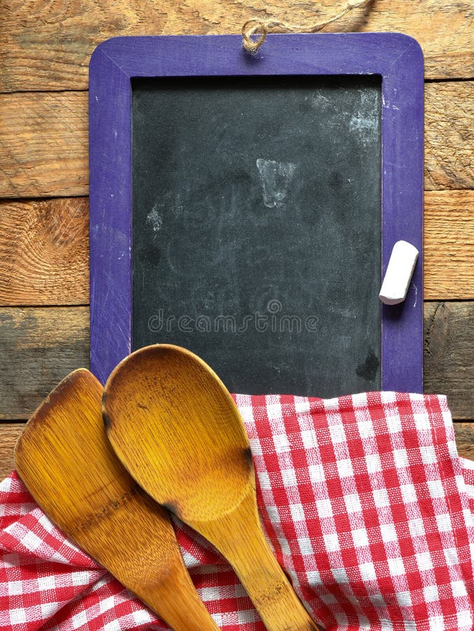 Restaurant menu on a chalk board with a kitchen cloth on a wooden table. High resolution photography ideal as a background for restaurants or chefs. Empty space to enter text, top view. Restaurant menu on a chalk board with a kitchen cloth on a wooden table. High resolution photography ideal as a background for restaurants or chefs. Empty space to enter text, top view