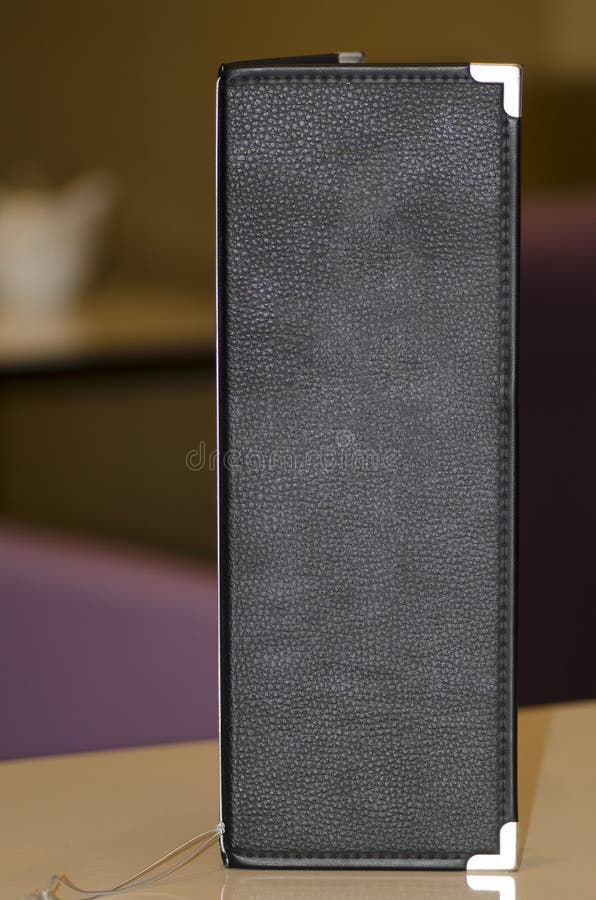 Close-up of a black leather restaurant menu on a table. Close-up of a black leather restaurant menu on a table