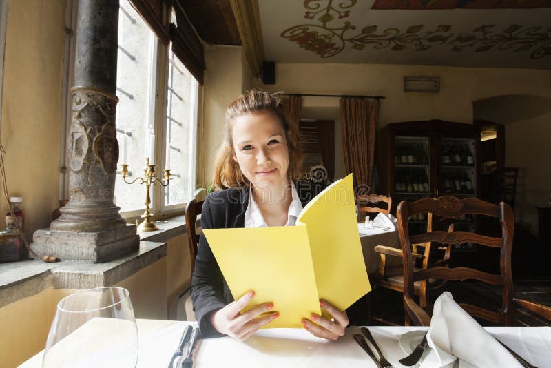 Smiling customer holding menu at restaurant table. Smiling customer holding menu at restaurant table