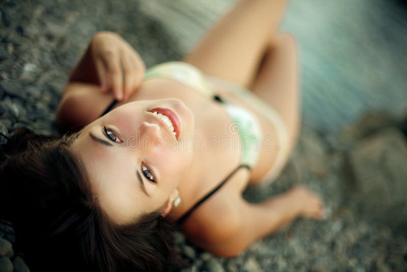 Menzogne di modello del brunette allegro sulla spiaggia immagine stock