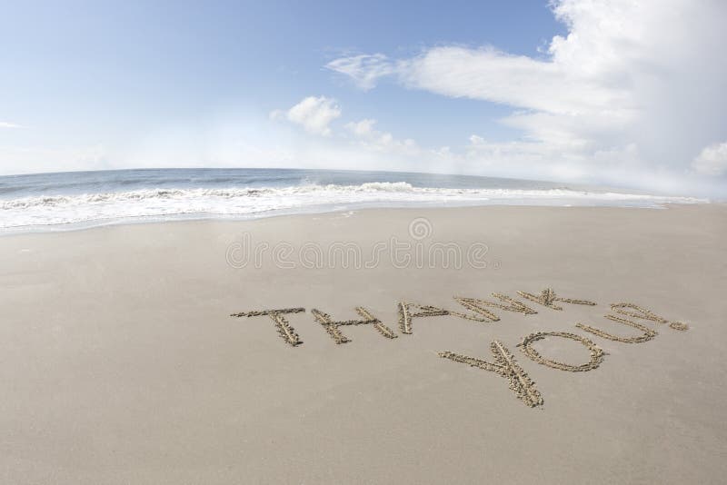 The words thank you written in the sand on the beach with a beautiful blue sky. The words thank you written in the sand on the beach with a beautiful blue sky