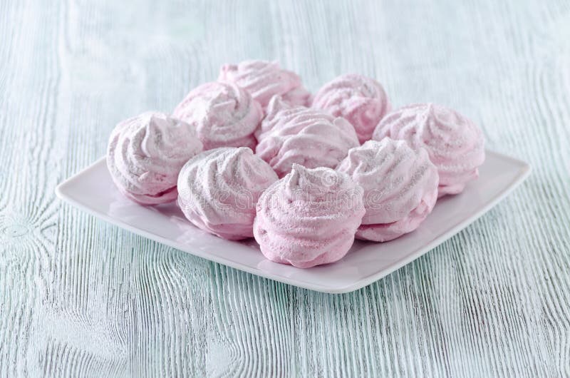 Merengues preciosos de la rosa del pastel, céfiros, melcochas en la tabla de madera del vintage fotografía de archivo libre de regalías Merengues preciosos de la rosa del pastel, céfiros, melcochas en la tabla de madera del vintage fotografía de archivo libre de regalías