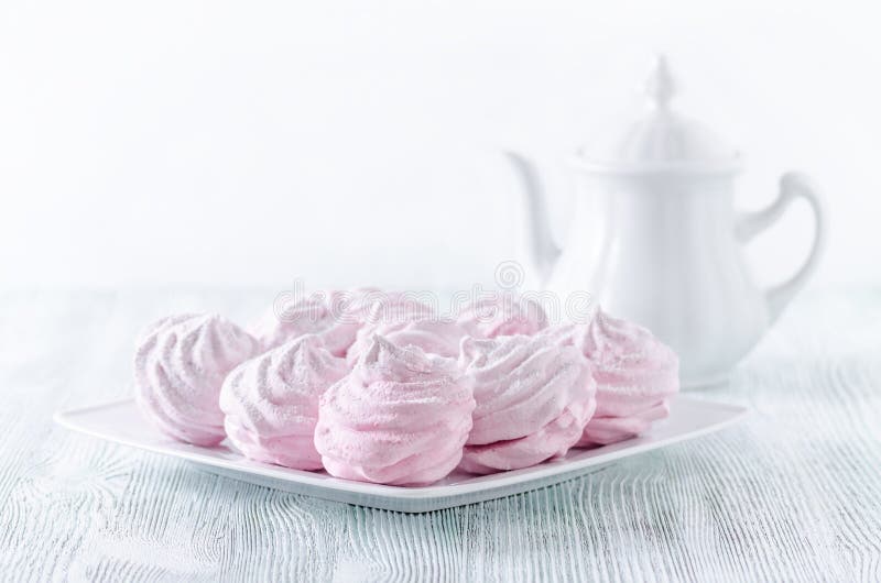Merengues preciosos de la rosa del pastel, céfiros, melcochas y un pote del café en la tabla de madera del vintage fotos de archivo libres de regalías Merengues preciosos de la rosa del pastel, céfiros, melcochas y un pote del café en la tabla de madera del vintage fotos de archivo libres de regalías