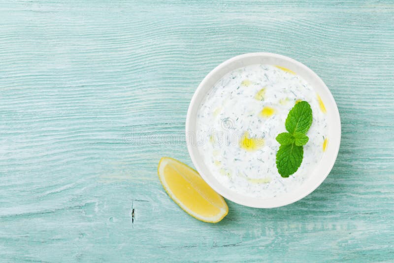 Dip sauce or dressing tzatziki from greek yogurt decorated with lemon, mint and olive oil from above. Dip sauce or dressing tzatziki from greek yogurt decorated with lemon, mint and olive oil from above.