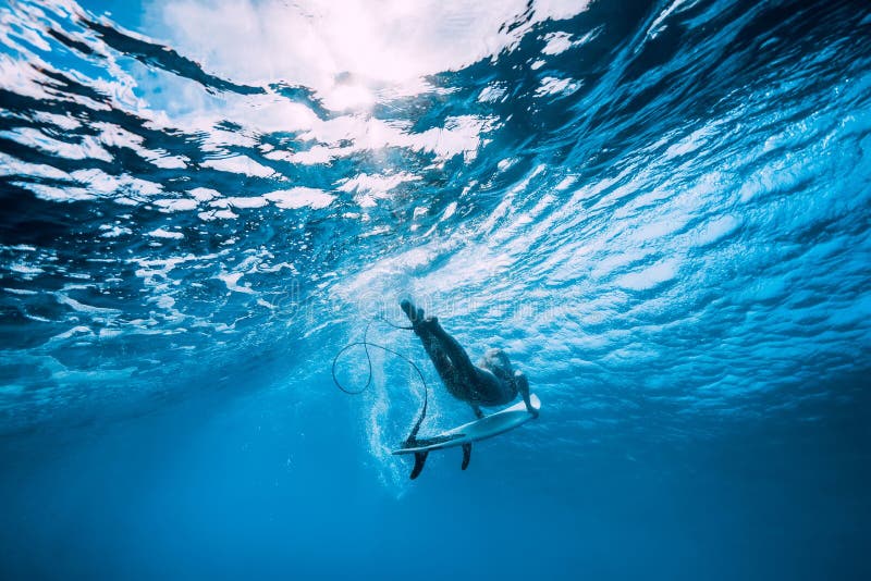 Attractive surfer woman dive underwater with under wave in blue ocean. Attractive surfer woman dive underwater with under wave in blue ocean