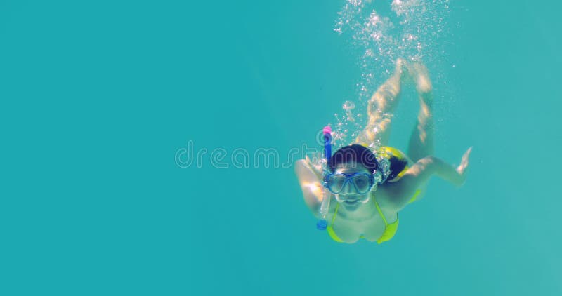 Mergulho moreno bonito no tubo de respiração vestindo da piscina