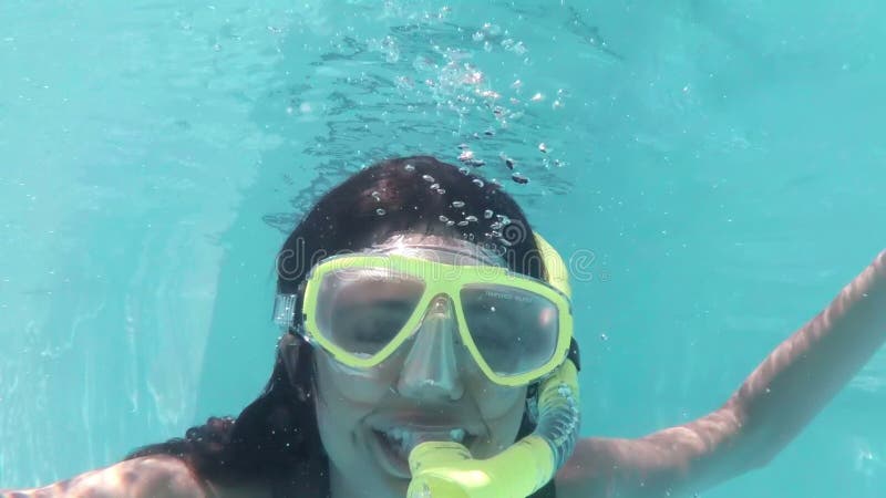 Mergulho moreno bonito no tubo de respiração vestindo da piscina