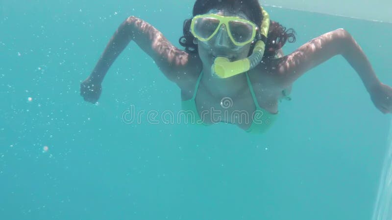 Mergulho moreno bonito no tubo de respiração vestindo da piscina