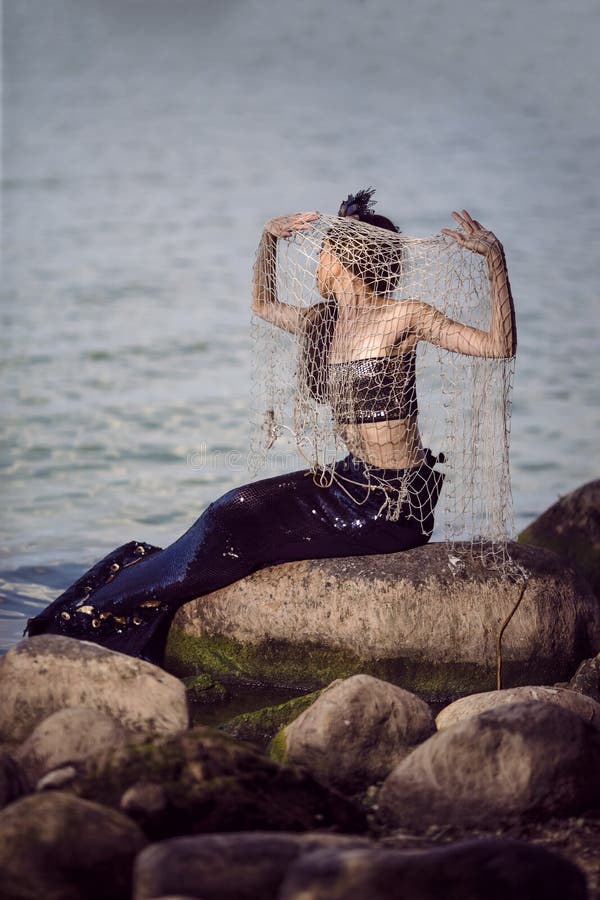 https://thumbs.dreamstime.com/b/mermaid-lady-covered-net-sea-coast-rocks-wearing-seashell-decorated-crown-black-shiny-tail-body-covered-237423557.jpg