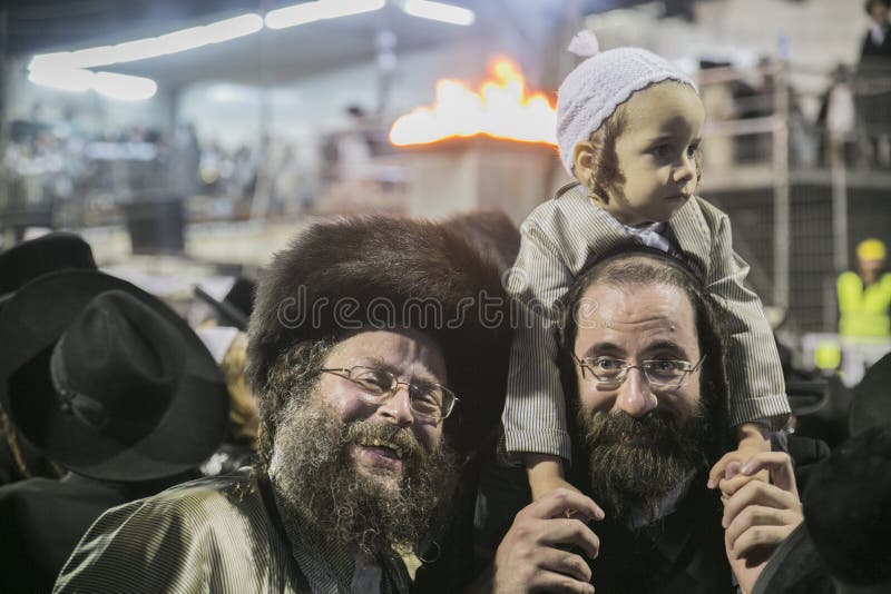 MERON,ISRAEL- MAY 26, 2016: An unidentified adorable Hasidic boy rejoices on his fathers' shoulders while wearing his fathers stock photo