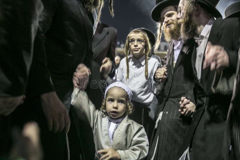MERON,ISRAEL- MAY 26, 2016: An unidentified adorable Hasidic boy rejoices on his fathers' shoulders while wearing his fathers royalty free stock photo
