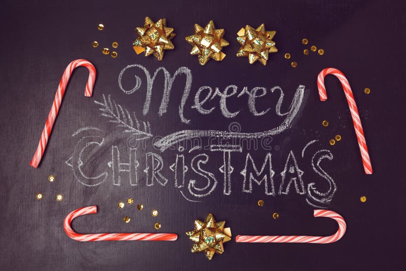 Merry Christmas greeting card design with chalkboard lettering and candy canes. View from above