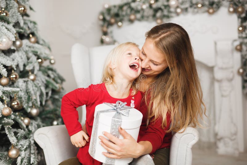 Merry Christmas and Happy Holidays. Cheerful mom and her cute daughter girl exchanging gifts stock photo Merry Christmas and Happy Holidays. Cheerful mom and her cute daughter girl exchanging gifts stock photo
