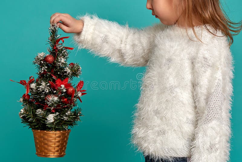 Merry Christmas and happy holidays. Cute little baby girl holding a Christmas tree. Christmas holiday concept.
