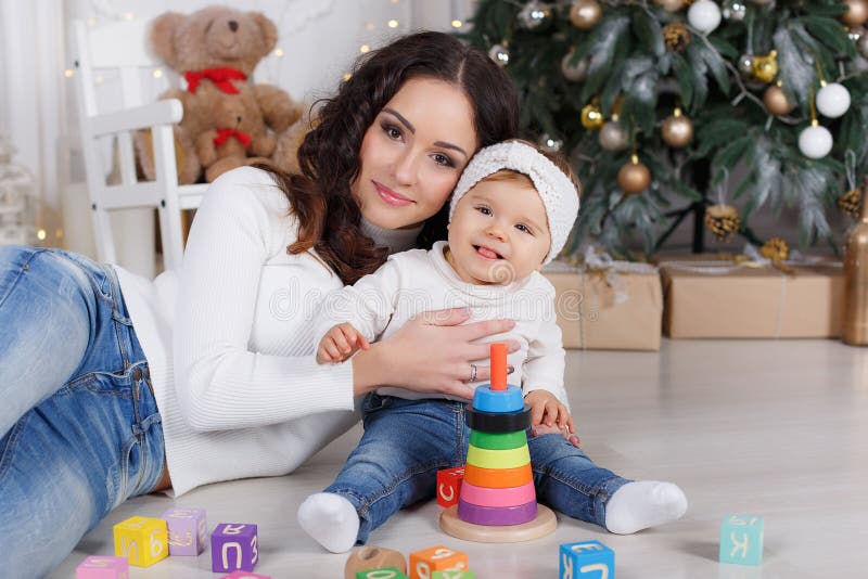 Mom with a little daughter playing on Christmas Eve on the background of a beautiful Christmas tree royalty free stock photos Mom with a little daughter playing on Christmas Eve on the background of a beautiful Christmas tree royalty free stock photos