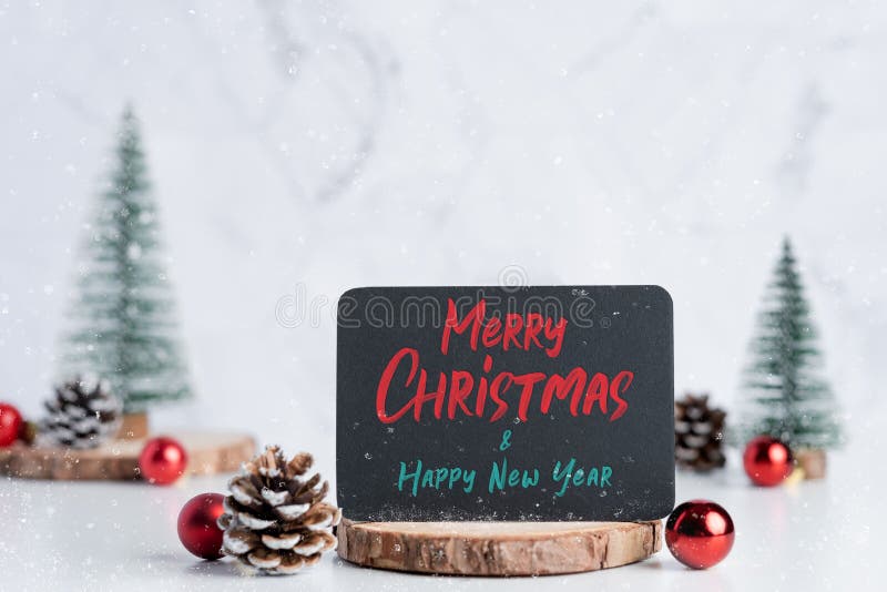 Merry christmas and happy new year on blackboard with christmas tree with pine cone and decor ball on white table and marble tile