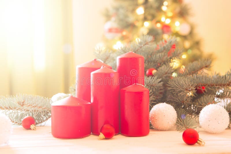 Merry Christmas! Red advent flower arrangement with burning candles on Cristmas Tree background stock image Merry Christmas! Red advent flower arrangement with burning candles on Cristmas Tree background stock image