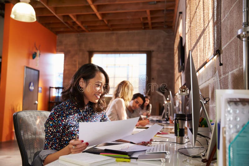Mesas de Team Of Designers Working At no escritório moderno fotografia de stock royalty free Mesas de Team Of Designers Working At no escritório moderno fotografia de stock royalty free