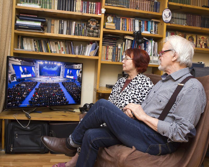 Message to the Parliament of the Russian President. ULAN - UDE, RUSSIA - February 20, 2019: a married couple of Russian pensioners at home are watching on TV the royalty free stock image Message to the Parliament of the Russian President. ULAN - UDE, RUSSIA - February 20, 2019: a married couple of Russian pensioners at home are watching on TV the royalty free stock image