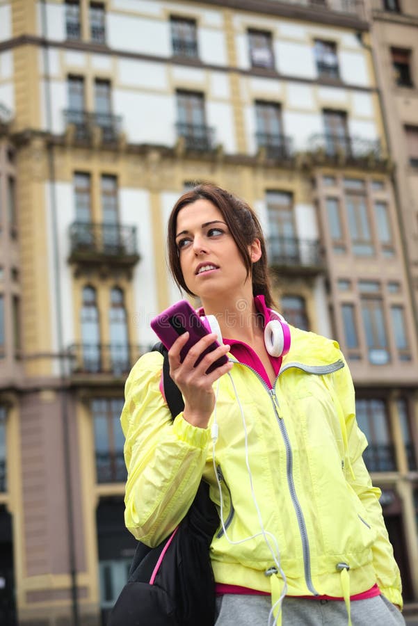 Messaggio mandante un sms della donna urbana sportiva sullo smartphone in via immagine stock Messaggio mandante un sms della donna urbana sportiva sullo smartphone in via immagine stock