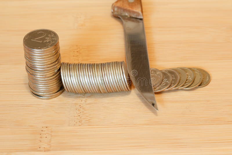 Messer, das einen Stapel der Münze schneidet Konzept von Etatverkürzungen, Einsparungen, r lizenzfreie stockfotos Messer, das einen Stapel der Münze schneidet Konzept von Etatverkürzungen, Einsparungen, r lizenzfreie stockfotos