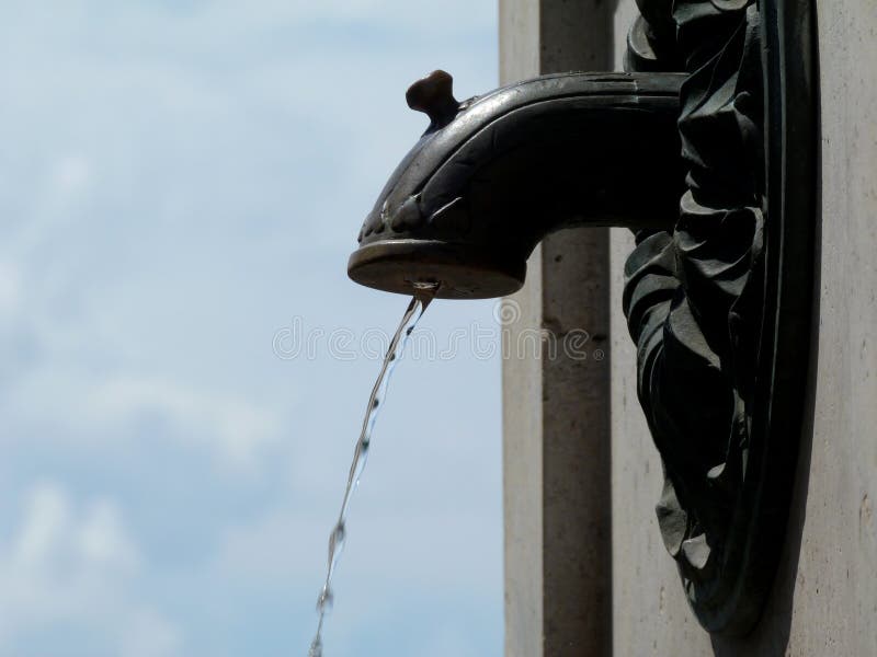 Messingwassertülle der klassischen Art unter blauem Himmel. WASSERtüllendetail der klassischen Art parken Messingunter blauem Himmel mit den weißen Wolken, die befestigt werden, um gut zu entsteinen öffentlich