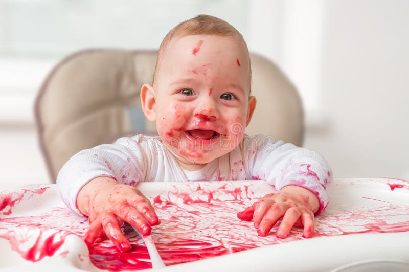 Messy and dirty baby is eating snack with hands royalty free stock photography