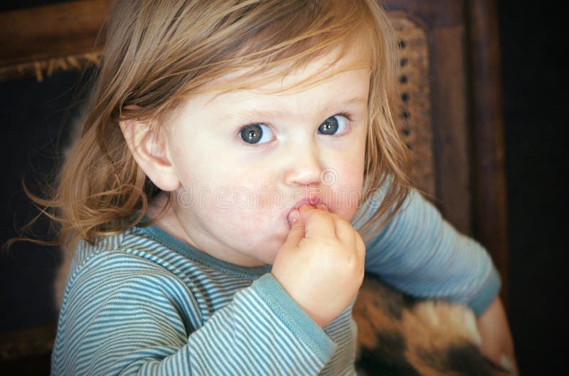 Portrét roztomilé modré oči batole jíst messily s rukama nebo uvedení hračky do úst.
