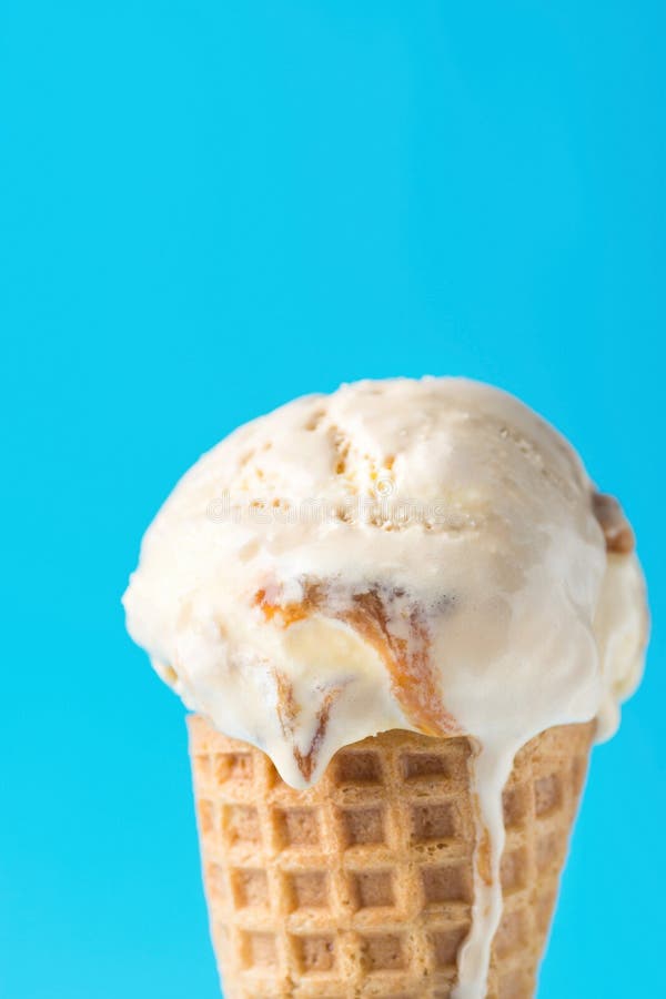 Mestolo del gelato alla vaniglia salato di fusione delizioso della caramella del caramello nel cono della cialda su fondo blu Dol