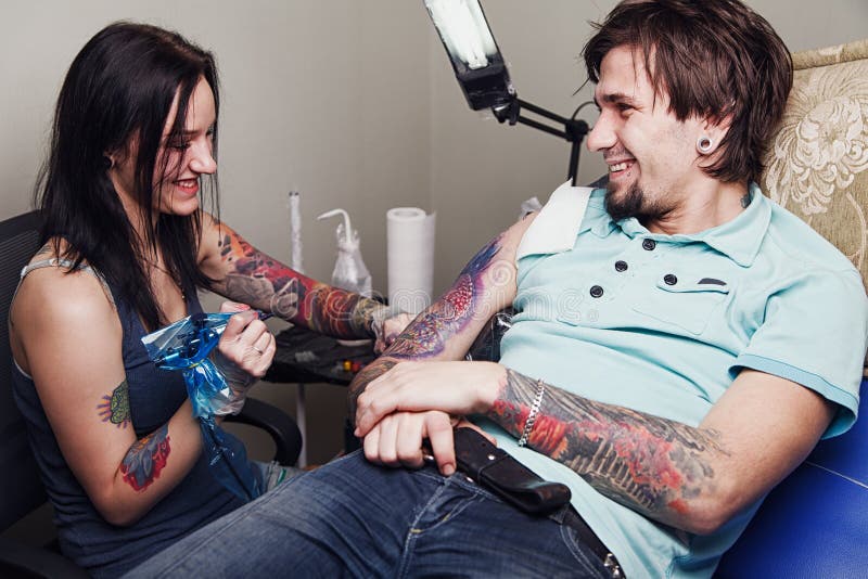 Mestre da tatuagem e homem fêmeas felizes do adulto fotografia de stock royalty free Mestre da tatuagem e homem fêmeas felizes do adulto fotografia de stock royalty free