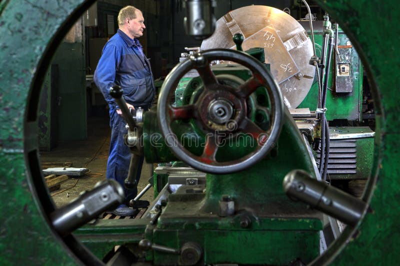Metaalverwerking op grote draaibank, de exploitantcontrole van de keerdermachine stock foto's Metaalverwerking op grote draaibank, de exploitantcontrole van de keerdermachine stock foto's