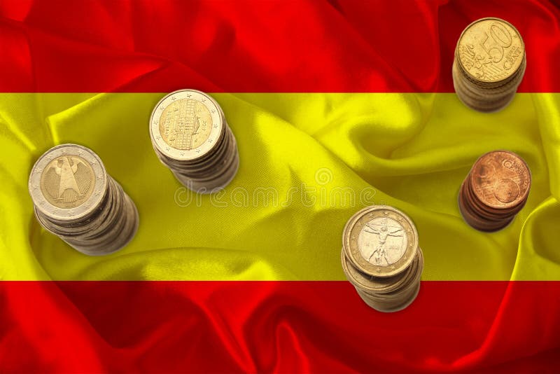 Metal currency coins against the background of the national flag of Spain, the concept of financial development, devaluation